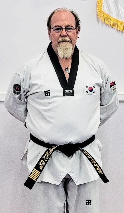 Taekwondo instructor in white gi with black belt and rank insignia
